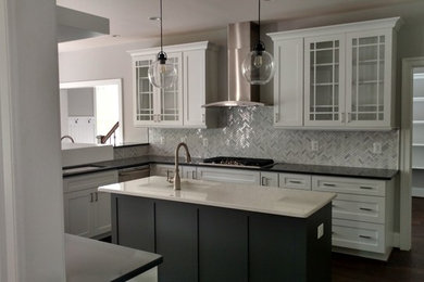 Inspiration for a mid-sized timeless u-shaped dark wood floor and black floor enclosed kitchen remodel in DC Metro with an undermount sink, glass-front cabinets, white cabinets, quartz countertops, gray backsplash, porcelain backsplash, stainless steel appliances and an island