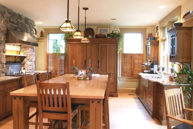 Large arts and crafts u-shaped light wood floor eat-in kitchen photo in San Francisco with a farmhouse sink, shaker cabinets, medium tone wood cabinets, granite countertops, stone slab backsplash, paneled appliances and an island