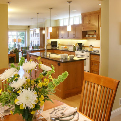 Open concept kitchen - mid-sized craftsman u-shaped light wood floor open concept kitchen idea in Los Angeles with an undermount sink, shaker cabinets, medium tone wood cabinets, granite countertops, brown backsplash, glass tile backsplash, white appliances and an island