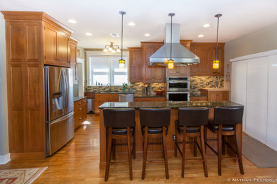 Ejemplo de cocina comedor de estilo americano grande con armarios estilo shaker, encimera de granito, salpicadero de azulejos tipo metro, electrodomésticos de acero inoxidable, suelo de madera clara y una isla