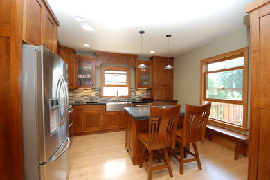 Example of a mid-sized classic l-shaped light wood floor eat-in kitchen design in Minneapolis with a farmhouse sink, shaker cabinets, granite countertops, multicolored backsplash, glass tile backsplash and stainless steel appliances
