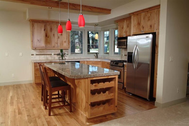 Arts and crafts medium tone wood floor kitchen photo in Other with a double-bowl sink, raised-panel cabinets, medium tone wood cabinets, granite countertops, stainless steel appliances and an island