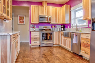 Example of a mid-sized arts and crafts u-shaped medium tone wood floor and brown floor eat-in kitchen design in Portland with a farmhouse sink, recessed-panel cabinets, light wood cabinets, granite countertops, stainless steel appliances, no island and gray countertops