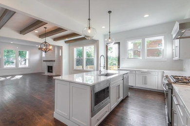 Inspiration for a large transitional l-shaped dark wood floor open concept kitchen remodel in Nashville with a single-bowl sink, shaker cabinets, white cabinets, quartzite countertops, white backsplash, subway tile backsplash, stainless steel appliances and an island