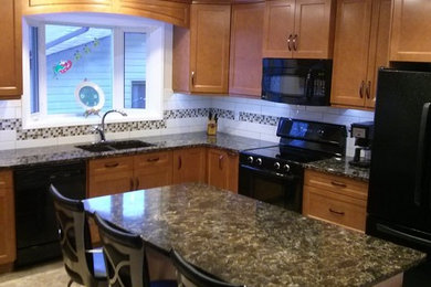 カルガリーにある広いトラディショナルスタイルのおしゃれなキッチン (アンダーカウンターシンク、シェーカースタイル扉のキャビネット、中間色木目調キャビネット、白いキッチンパネル、サブウェイタイルのキッチンパネル、黒い調理設備) の写真