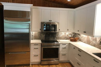 Inspiration for a large timeless l-shaped light wood floor and yellow floor open concept kitchen remodel in Toronto with an undermount sink, shaker cabinets, white cabinets, quartz countertops, multicolored backsplash, stone tile backsplash, stainless steel appliances, an island and beige countertops