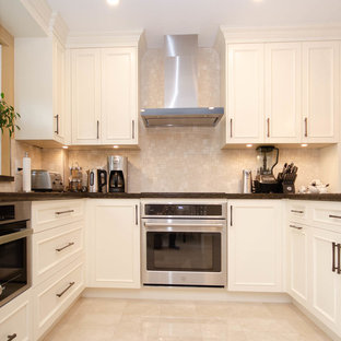 Large transitional u-shaped eat-in kitchen in Toronto with a double-bowl sink, recessed-panel cabinets, white cabinets, quartzite benchtops, beige splashback, ceramic splashback, stainless steel appliances, porcelain floors, a peninsula, beige floor and brown benchtop.