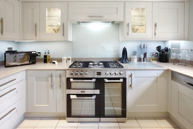 This is an example of a medium sized contemporary u-shaped enclosed kitchen in West Midlands with a double-bowl sink, shaker cabinets, beige cabinets, quartz worktops, glass sheet splashback, stainless steel appliances, ceramic flooring, no island and beige floors.