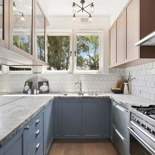 Small transitional u-shaped separate kitchen in Sydney with an undermount sink, shaker cabinets, blue cabinets, marble benchtops, white splashback, ceramic splashback, stainless steel appliances, dark hardwood floors, no island, brown floor and white benchtop.