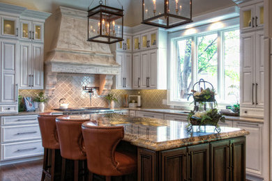 Example of a transitional medium tone wood floor kitchen design in Charleston with an undermount sink, raised-panel cabinets, white cabinets, granite countertops, beige backsplash, paneled appliances and an island