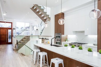 Inspiration for a large contemporary galley light wood floor and beige floor open concept kitchen remodel in Toronto with flat-panel cabinets, white cabinets, quartzite countertops, paneled appliances, an undermount sink, white backsplash, stone slab backsplash and an island