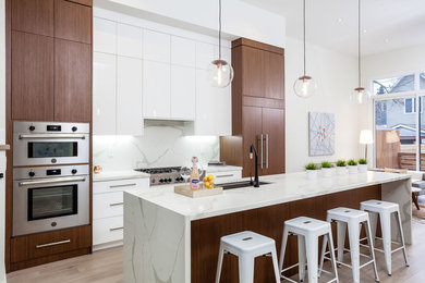 Photo of a medium sized contemporary galley open plan kitchen in Toronto with a submerged sink, flat-panel cabinets, white cabinets, white splashback, integrated appliances, light hardwood flooring, an island, beige floors, marble worktops and marble splashback.