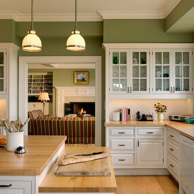 Inspiration for a timeless enclosed kitchen remodel in New York with glass-front cabinets, wood countertops, white cabinets, an undermount sink, white backsplash and white appliances