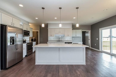 Eat-in kitchen - mid-sized modern l-shaped medium tone wood floor eat-in kitchen idea in Other with an undermount sink, shaker cabinets, white cabinets, quartz countertops, gray backsplash, glass tile backsplash, stainless steel appliances and an island