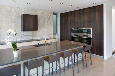 Inspiration for a large modern l-shaped limestone floor and beige floor open concept kitchen remodel in Calgary with an undermount sink, dark wood cabinets, quartz countertops, white backsplash, stone slab backsplash, stainless steel appliances, flat-panel cabinets and an island