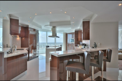 Open concept kitchen - large u-shaped porcelain tile open concept kitchen idea in Miami with a double-bowl sink, flat-panel cabinets, medium tone wood cabinets, quartz countertops, white backsplash, stone slab backsplash, stainless steel appliances and an island