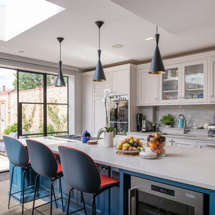 Photo of a classic galley kitchen in London with a submerged sink, shaker cabinets, beige cabinets, grey splashback, metro tiled splashback, dark hardwood flooring, an island, brown floors and beige worktops.