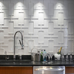 Foto de cocina comedor en L, minimalista, con electrodomésticos de acero inoxidable, fregadero de un seno, armarios con paneles lisos, puertas de armario de madera oscura, encimera de granito, salpicadero blanco y salpicadero de azulejos de cerámica