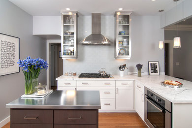 Exempel på ett modernt kök, med luckor med glaspanel, skåp i rostfritt stål, marmorbänkskiva, vitt stänkskydd, stänkskydd i tunnelbanekakel och rostfria vitvaror