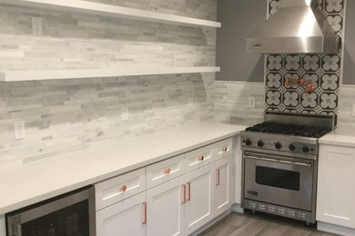 Mid-sized transitional galley dark wood floor enclosed kitchen photo in San Francisco with a double-bowl sink, shaker cabinets, white cabinets, solid surface countertops, gray backsplash, stone tile backsplash and no island