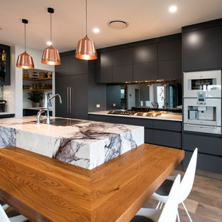 Inspiration for a contemporary l-shaped kitchen in Brisbane with grey cabinets, marble benchtops, mirror splashback, with island, medium hardwood floors, an undermount sink, flat-panel cabinets, white appliances, brown floor and white benchtop.