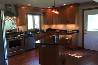 Mid-sized elegant l-shaped eat-in kitchen photo in Boston with an undermount sink, shaker cabinets, medium tone wood cabinets, granite countertops, beige backsplash, stainless steel appliances and an island