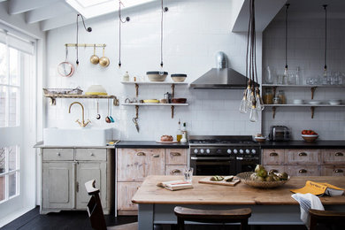Exempel på ett mellanstort industriellt svart linjärt svart kök och matrum, med granitbänkskiva, vitt stänkskydd, rostfria vitvaror, en rustik diskho, skåp i slitet trä och mörkt trägolv