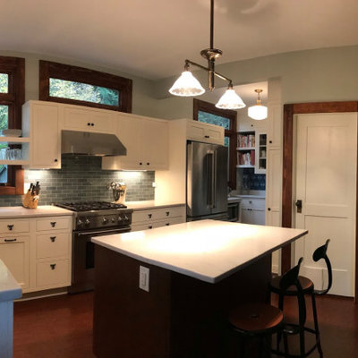 Example of an arts and crafts medium tone wood floor kitchen pantry design in Seattle with an undermount sink, shaker cabinets, white cabinets, onyx countertops, green backsplash, glass tile backsplash, stainless steel appliances, an island and white countertops