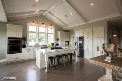 Example of a large transitional l-shaped dark wood floor and brown floor eat-in kitchen design in Cincinnati with a farmhouse sink, shaker cabinets, white cabinets, granite countertops, stainless steel appliances and an island