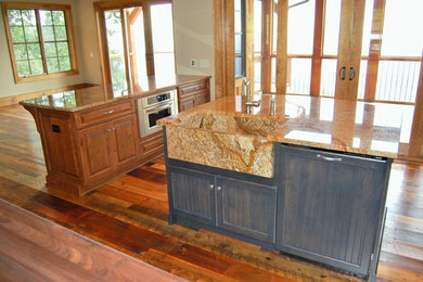Mountain style kitchen photo in Charlotte with a farmhouse sink, raised-panel cabinets, medium tone wood cabinets, granite countertops, stainless steel appliances and an island