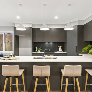 This is an example of a mid-sized contemporary u-shaped open plan kitchen in Other with a single-bowl sink, flat-panel cabinets, grey cabinets, laminate benchtops, grey splashback, ceramic splashback, stainless steel appliances, medium hardwood floors, with island, brown floor and white benchtop.