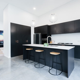 Design ideas for a contemporary kitchen in Sydney with an undermount sink, flat-panel cabinets, black cabinets, white splashback, stainless steel appliances, concrete floors, with island, grey floor, white benchtop and vaulted.
