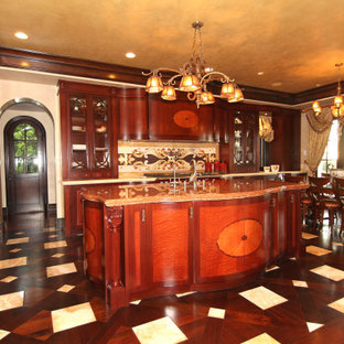 Foto de cocina comedor en L, mediterránea, de tamaño medio, con fregadero bajoencimera, armarios con paneles lisos, puertas de armario de madera en tonos medios, encimera de mármol, salpicadero beige, salpicadero de azulejos de piedra, electrodomésticos con paneles, suelo de madera oscura, una isla, suelo marrón y encimeras naranjas
