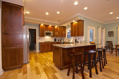Ejemplo de cocina clásica renovada cerrada sin isla con salpicadero blanco, electrodomésticos de acero inoxidable y suelo de madera clara