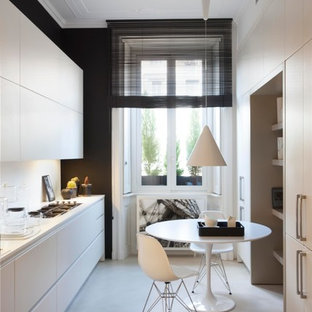 Esempio di una cucina parallela design chiusa e di medie dimensioni con lavello integrato, elettrodomestici in acciaio inossidabile, pavimento in cemento, nessuna isola, pavimento beige, ante lisce, ante bianche e paraspruzzi bianco