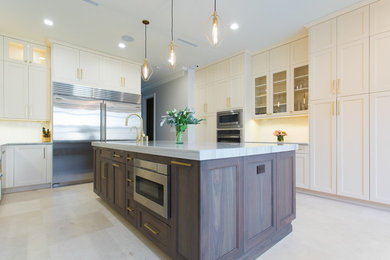 Large trendy galley travertine floor and beige floor eat-in kitchen photo in New York with an undermount sink, recessed-panel cabinets, quartz countertops, stainless steel appliances, an island, beige cabinets, white backsplash, porcelain backsplash and gray countertops