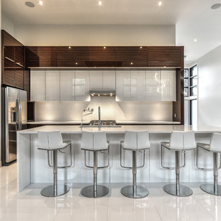 Esempio di un'ampia cucina a L minimalista con ante di vetro, ante in legno bruno, top in quarzo composito, elettrodomestici in acciaio inossidabile e isola