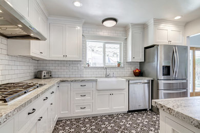 Example of a small farmhouse galley ceramic tile kitchen pantry design in San Diego with a farmhouse sink, shaker cabinets, white cabinets, granite countertops, white backsplash, porcelain backsplash, stainless steel appliances and a peninsula