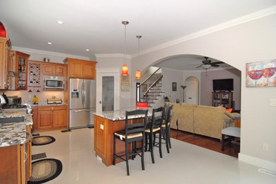 Example of a classic l-shaped porcelain tile open concept kitchen design in Portland Maine with raised-panel cabinets, medium tone wood cabinets, granite countertops, stainless steel appliances, an island and a single-bowl sink