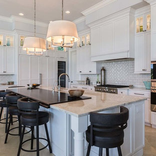 This is an example of a mid-sized beach style l-shaped open plan kitchen in Other with a single-bowl sink, recessed-panel cabinets, white cabinets, white splashback, glass tile splashback, stainless steel appliances, ceramic floors and with island.