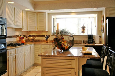 Example of a mid-sized classic ceramic tile kitchen design in Chicago with white cabinets, granite countertops, beige backsplash, ceramic backsplash, an island, a double-bowl sink, louvered cabinets and black appliances