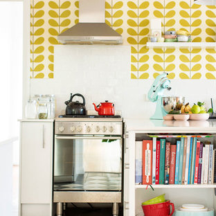 This is an example of an eclectic kitchen in Newcastle - Maitland with flat-panel cabinets, white cabinets, stainless steel appliances, multi-coloured floor and white benchtop.