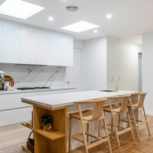 Inspiration for a contemporary l-shaped kitchen in Canberra - Queanbeyan with an undermount sink, quartz benchtops, white splashback, stone slab splashback, light hardwood floors, with island, flat-panel cabinets, white cabinets, panelled appliances, beige floor and white benchtop.