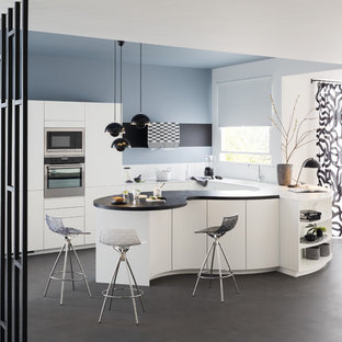 Diseño de cocina en U, actual, de tamaño medio, abierta, con fregadero encastrado, armarios con paneles lisos, puertas de armario blancas, salpicadero blanco, electrodomésticos de acero inoxidable, península y suelo gris