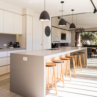 Inspiration for a contemporary galley kitchen in Other with a double-bowl sink, flat-panel cabinets, white cabinets, grey splashback, light hardwood floors, with island, beige floor and grey benchtop.