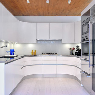 Inspiration for a small contemporary u-shaped separate kitchen in DC Metro with an integrated sink, flat-panel cabinets, white cabinets, stainless steel benchtops, glass sheet splashback, stainless steel appliances, bamboo floors and white splashback.