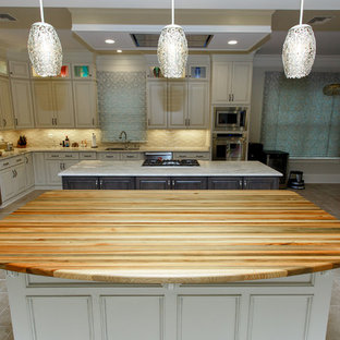 Design ideas for a large contemporary eat-in kitchen in New Orleans with an undermount sink, beaded inset cabinets, white cabinets, wood benchtops, stainless steel appliances, ceramic floors, with island, white floor and green benchtop.