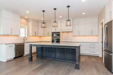Elegant medium tone wood floor eat-in kitchen photo in Other with white cabinets, granite countertops, white backsplash, porcelain backsplash, stainless steel appliances, an island and white countertops