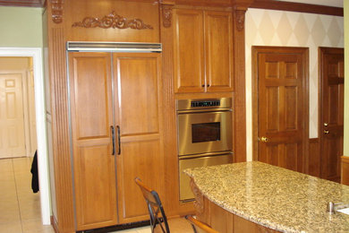 Example of a classic u-shaped terra-cotta tile kitchen pantry design in Other with raised-panel cabinets, medium tone wood cabinets, granite countertops, paneled appliances, an island and an undermount sink