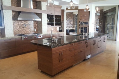 Example of a large trendy l-shaped ceramic tile open concept kitchen design in Las Vegas with a farmhouse sink, flat-panel cabinets, dark wood cabinets, granite countertops, brown backsplash, mosaic tile backsplash, stainless steel appliances and an island